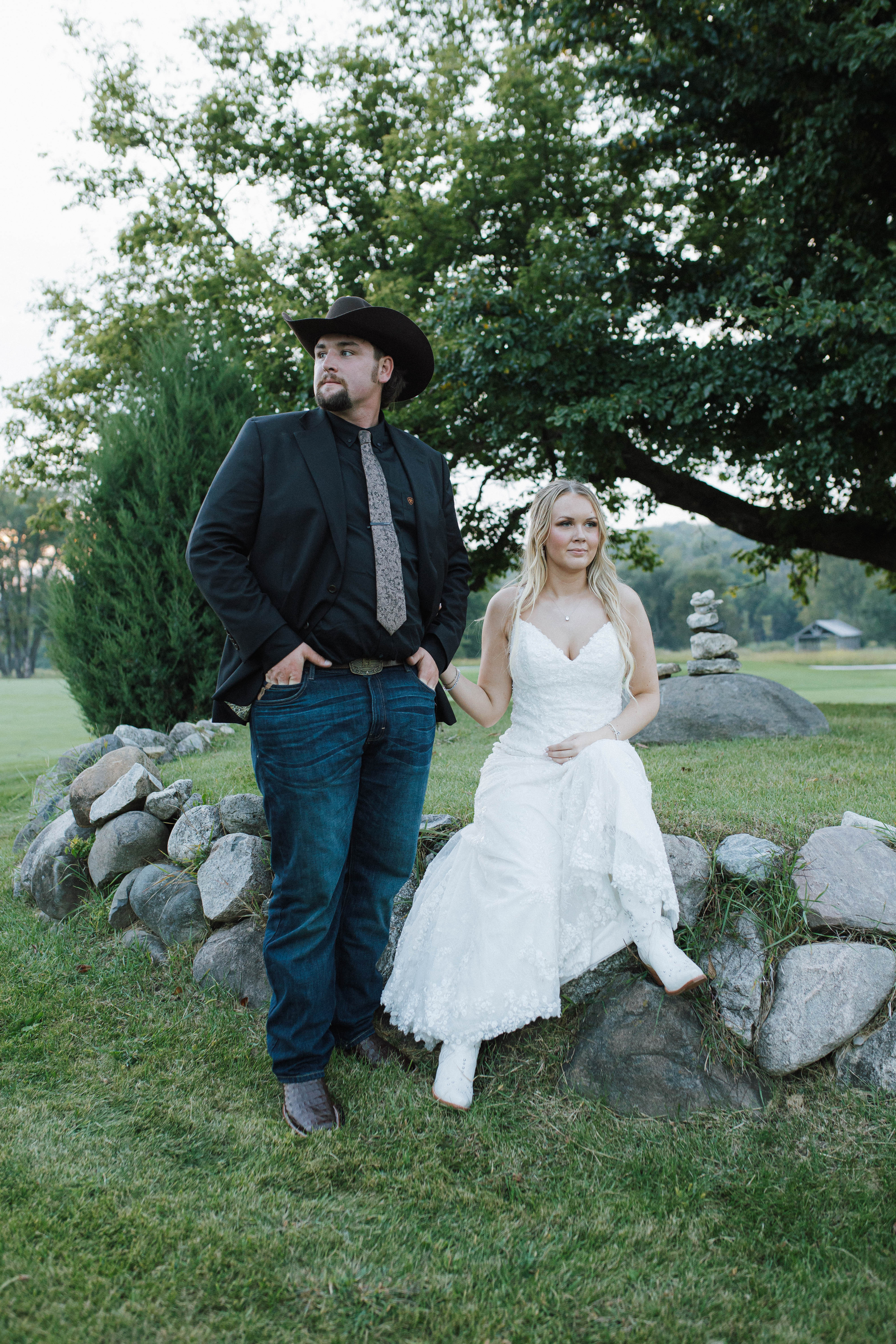 Wisconsin wedding photographer - country western wedding portrait with groom in cowboy hat and bride in white boots sitting on stone wall