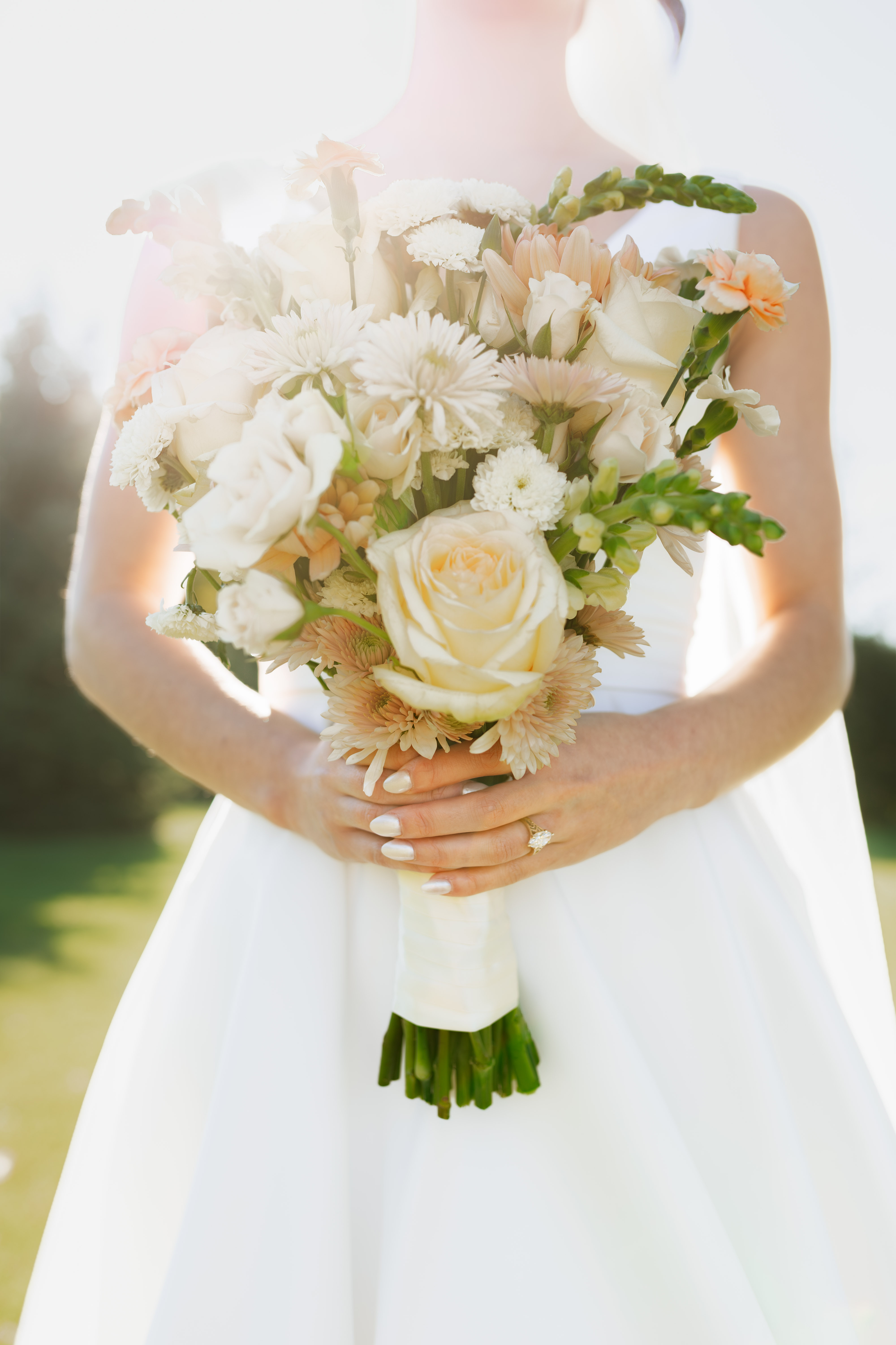 Bride holding wedding bouquet with engagement ring showing
