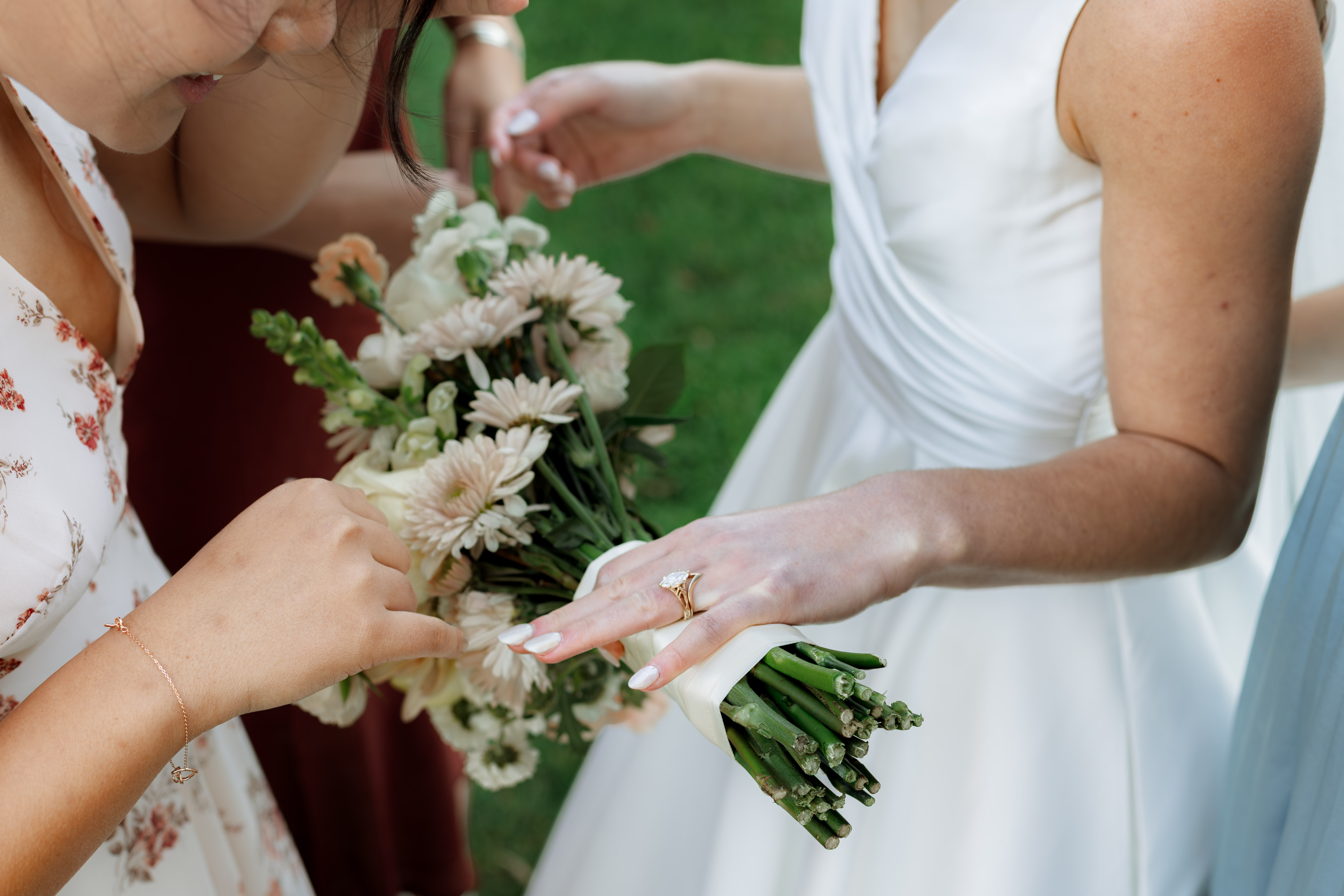 Bride and bridesmaid showing hands with engagement rings and bouquets