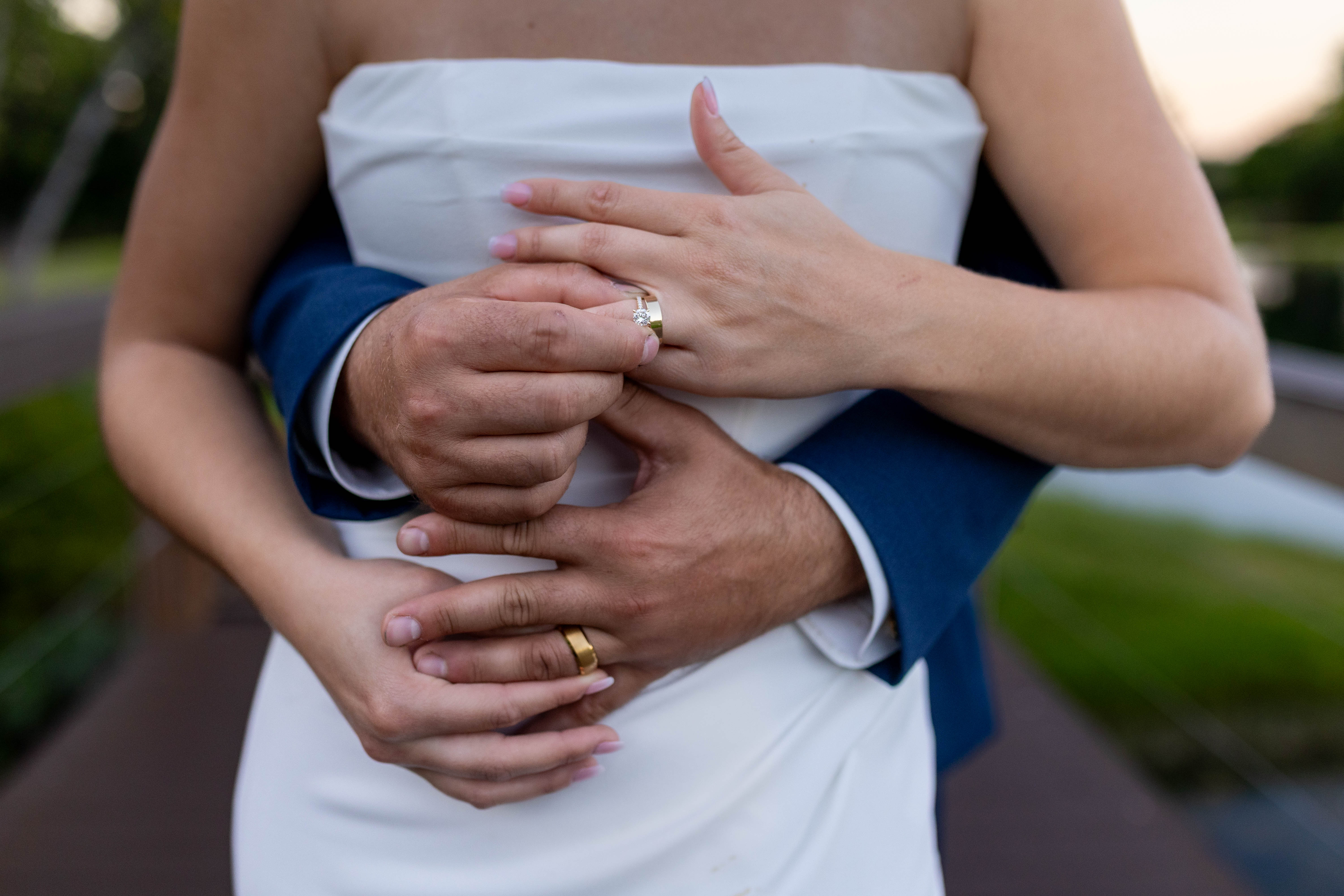 Wedding ring detail with hands embracing