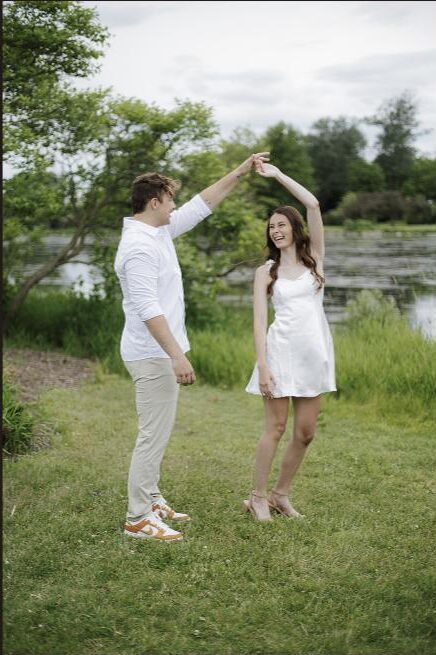 Engaged couple dancing and twirling by a pond in a Milwaukee park